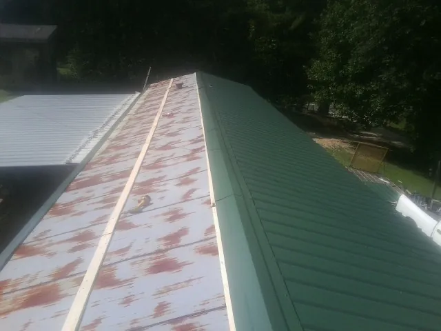 Old rusted panels beside newly installed green metal roofing — Wind Damage Roof Repair by Roofing Brothers in Quakertown