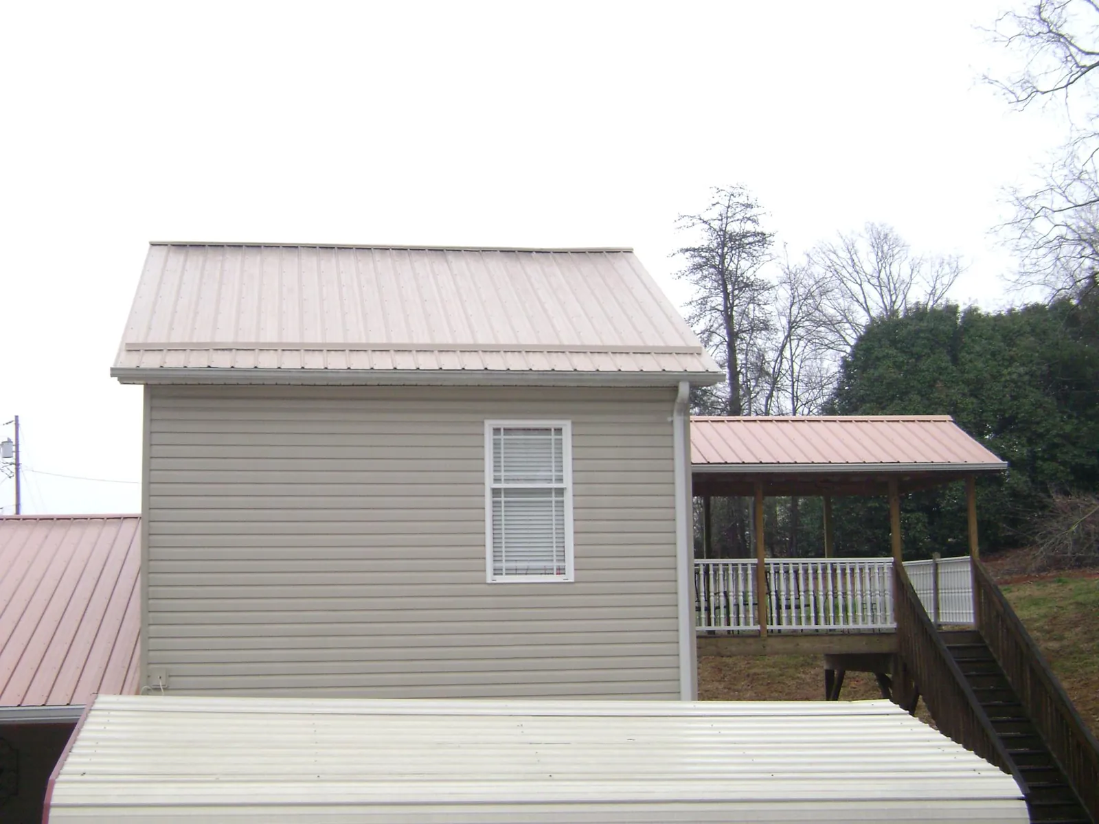 Tan metal roofs on a two story addition and attached porch, from a Roof Replacement job in Quakertown